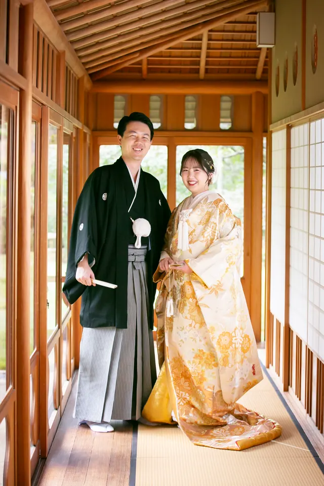 茶室の渡り廊下に立つ、金の色打掛の花嫁と新郎