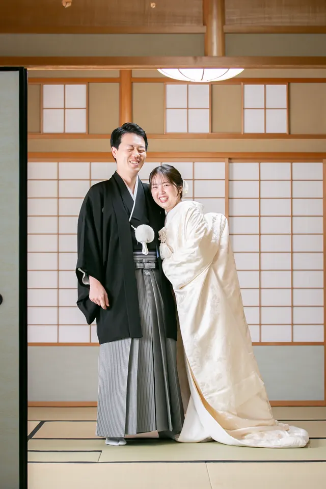 障子の座敷に立つ、白無垢の花嫁と新郎